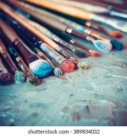 Artistic paintbrushes on artist canvas covered with oil paints