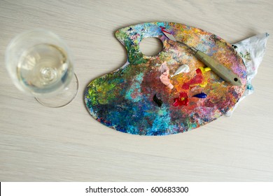 Artistic Palette With Paint, A Brush And A Palette Knife And A Glass Of White Wine