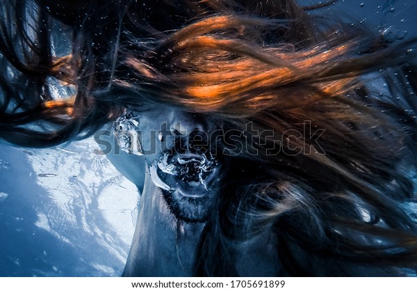 Artistic pic out of\
focus underwater with long hair man swimming with bubble in water,\
dark underwater atmosphere with nightmare human abyssal creature\
like mermaid with\
beard