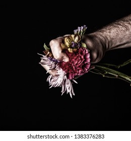 Artistic Picture Of Flowers Symbolically Being Crushed With Fist