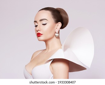 Artistic portrait of a beautiful, elegant woman in a white dress. Elegant style. A fashionable model in gold jewelry.