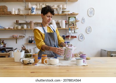 Artistic pottery master at work: happy woman in apron holding handmade jug working in ceramics studio. Craftswoman creating handicraft crockery in workshop. Craftsmanship and entrepreneurship concept - Powered by Shutterstock