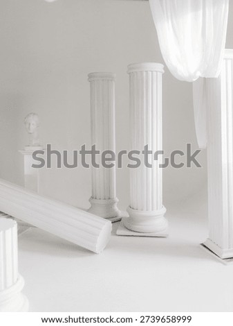 An artistic studio setup featuring white fluted architectural columns, including a fallen pillar on the floor, creating a 