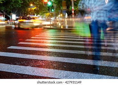 Artistic Style - Night View Of Crosswalk And Pedestrian At Modern City Zebra Crossing Street In Rainy Day. Blur Abstract.Background Concept.