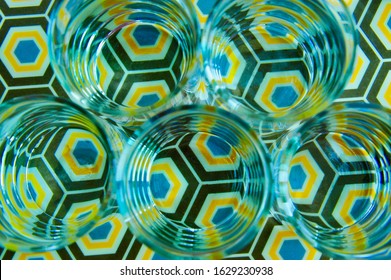 Artistic Top View Through Water Inside Several Clear Glasses Creating Distorted Image Of Colourful Octagonal Pattern And Infinity Effect Of Circular Shapes. Visual Perception And Refraction. 