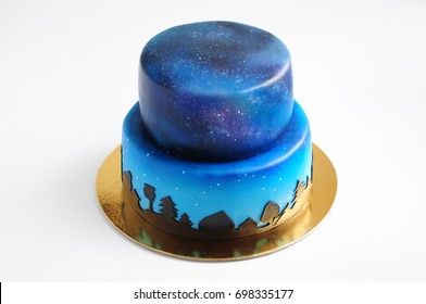 Artistic Two-tiered Cake With The Image Of The Cosmos Drawn By Airbrush. Galaxy, Stars In The Night Sky And Silhouettes Of Trees. Cutout. Picture For A Menu Or A Confectionery Catalog.