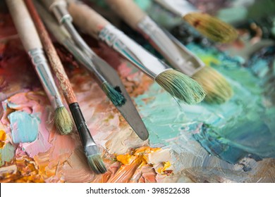 artists brushes and oil paints on wooden palette. macro artist's palette, texture mixed oil paints in different colors and saturation. palette with paintbrush and palette-knife. Brushes on canvas - Powered by Shutterstock