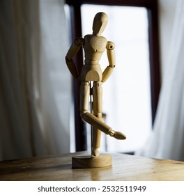 An artist's mannequin (lay figure) poses on the table, half-lit, half in shadow. The power of art. . - Powered by Shutterstock