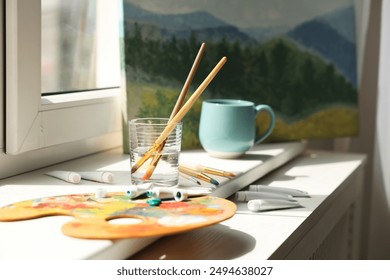 Artist's palette, brushes in glass of water and paints on window sill - Powered by Shutterstock