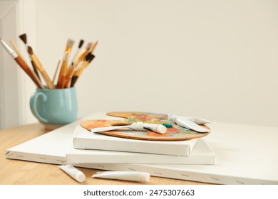 Artist's palette, paints and blank canvases on wooden table indoors, closeup - Powered by Shutterstock