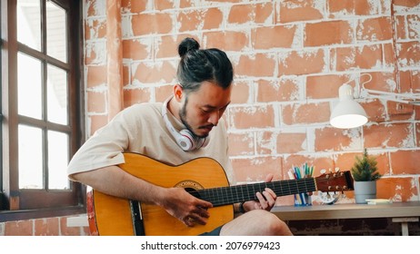Artists producing music in their home sound studio, Asian man playing guitar and singing in living room at home. Lifestyle man relax in morning at home concept. - Powered by Shutterstock