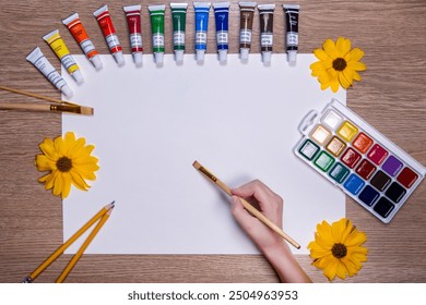 Artist's Workspace with Paint Tubes and Blank Canvas. A creative workspace featuring a blank white canvas surrounded by vibrant tubes of paint arranged in a semicircle on a wooden table. - Powered by Shutterstock