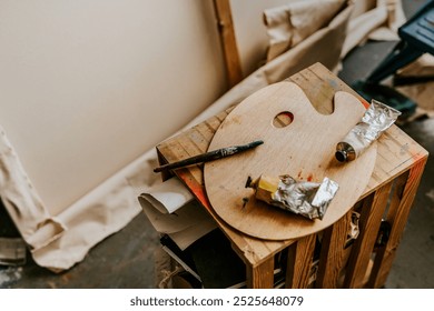 Artist's workspace with wooden color palette, paint tubes, and brushes. Creative art supplies on a table. Palette and paint for artistic expression. Photo of wooden color palette with paint - Powered by Shutterstock