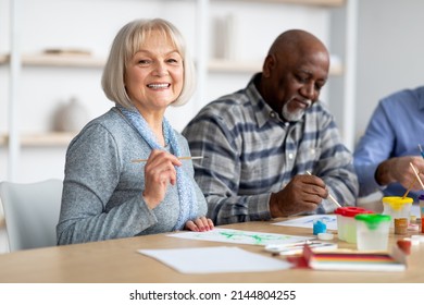 Art-therapy for seniors concept. Positive multiracial group of elderly people enjoying painting with brush, sitting around table, having good time together at assisted lliving, closeup photo - Powered by Shutterstock