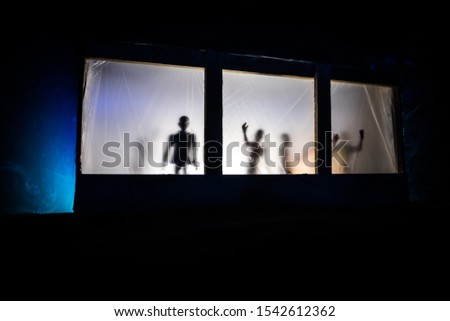 Artwork decoration. Old house with a big windows and zombies inside. Blurred scary silhouettes at window. Horror Halloween concept