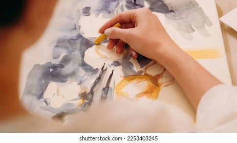Artwork painting. Visual art. Hobby inspiration. Female artist creating yellow blue color abstract design picture with wax crayon on paper canvas.
