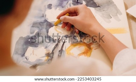Artwork painting. Visual art. Hobby inspiration. Female artist creating yellow blue color abstract design picture with wax crayon on paper canvas. 商業照片 © 