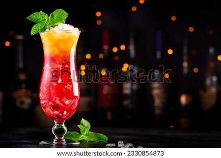 Aruba Ariba alcoholic cocktail drink with vodka, white rum, orange, lemon and pineapple juice, grenadine, dark bar counter background, copy space