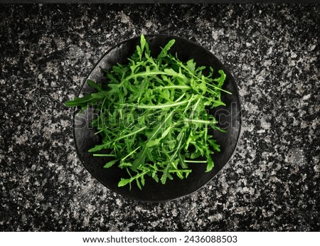 Arugula on Black Plate, Fresh Arugula, Ruccola Leaves, Rucola, Eruca or Garden Roquette Salad on Dark Background Top View [[stock_photo]] © 