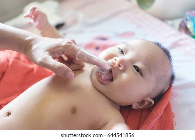 Asain Doctor ,nurse Or Mother Use Finger To Clean Baby Tongue And Gum With The Clean Gauze, First Brushing Teeth During Bathing Time.vintage Color