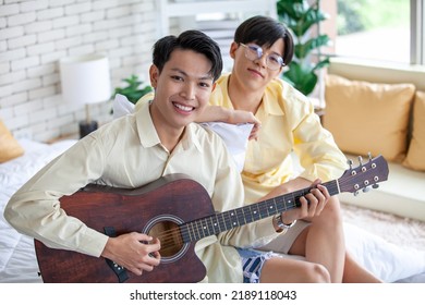 Asain Gay Couple Playing Guitar Together In Home, LGBTQ Concept.