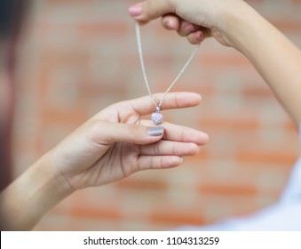 Asain girl holding necklace and heart shape pendant