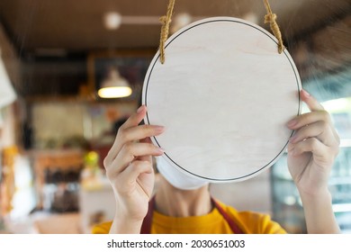 Asain Staff Woman Wearing Protection Face Mask Turning Blank Wodden Sign Board On Glass Door In Modern Cafe Coffee Shop, Hotel Service, Cafe Restaurant, Retail Store, Small Business Owner Concept