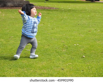 An Asain Toddler Is On Her Training To Walk In The Park