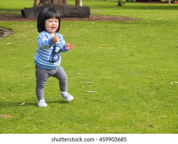 An Asain Toddler Is On Her Training To Walk In The Park