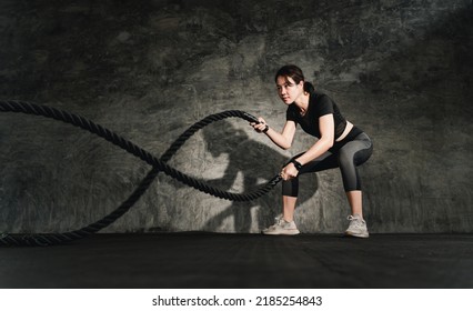 Asain Woman with battle rope battle ropes exercise in the fitness gym. CrossFit concept. gym, sport, rope, training, athlete, workout, exercises concept