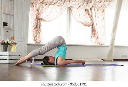 Asanas. Young Beautiful Girl Practicing Yoga At Home. Yoga Studio In The Daytime. 