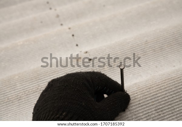 Asbestos roof. Asbestos cement roofing sheets,\
corrugated panels. dividing the sheet across with a nail and\
hammer. The perforation\
process
