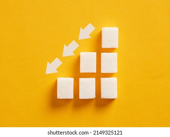 Ascending sugar cube graph with descending arrows indicating to reduce sugar intake and healthy nutrition. - Shutterstock ID 2149325121