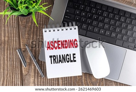 Ascending triangle phrase on notepad near laptop, pen and plant on wooden desk symbolizing bullish chart pattern . H
