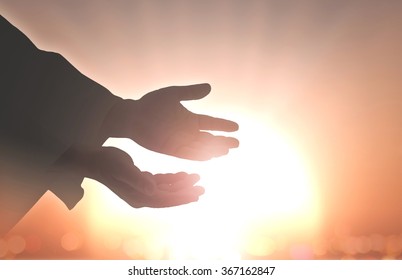 Ascension day concept: Silhouette hands of God over blurred autumn sunset background