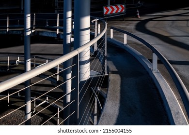 Ascent ramp driveway of big car park in Cologne Germany. Infrastructure building with steel and concrete construction illuminated by sunlight. Signpost with red and white arrows in dark background.