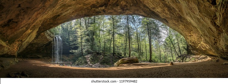 Ash Cave in Hocking Hills Ohio. A large waterfall cascades over the panoramic view of the river. 