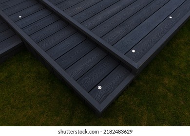 Ash Grey Composite Decking Built On Two Levels On A Residential Back Garden With Low Voltage Deck Lights Installed As Well And Illuminated. Good Image For A Landscape Gardiner