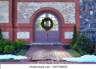 Asheville, NC / USA - Circa December 2018: A Simple, Green Christmas Holiday Wreath Hanging On A Set Of Double Doors With Small Piles Of Snow