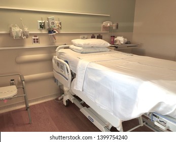 Asheville, NC / USA - May 14, 2019: An Empty Hospital Bed In An Empty Room Equipped With Medical Equipment. Shows The Base Of The Bed As Well As Partial Room.