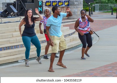 ASHEVILLE, NORTH CAROLINA, USA - SEPTEMBER 12, 2014: Four people smiling while line dancing outdoors