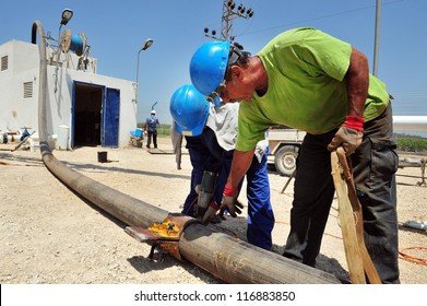 ASHKELON, ISR - AUGUST 05 2010: Water drilling engineers maintaining water pipe for Mekorot in Ashkelon, Israel.It supplies Israel with 90% of its drinking water and a cross-country water supply.