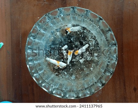 An ashtray filled with cigarette ash fragments, reflecting the passage of time and smoking activities. The ash-covered surface conveys a sense of intense usage, while the scattered ash particles signi
