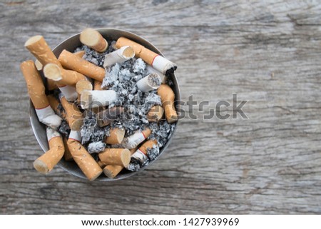 Ashtray full of cigarettes butts close-up on wood background