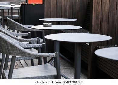 Ashtray on table for smoking outdoors. Empty tables and chairs outside restaurant or cafe or bar. 
