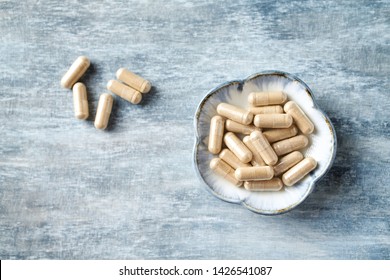 Ashwagandha (Withania somnifera) capsules. Concept for a healthy dietary supplementation. Rustic wooden background. Top view. Copy space. 