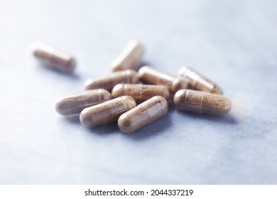 Ashwagandha (Withania somnifera) capsules. Concept for a healthy dietary supplementation. Bright stone background. Close up. 