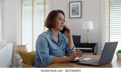 Asia adult people or SME owner woman leader moody sitting tired busy phone call work on laptop computer at desk house office think worry concern give advice on distance job crisis corporate trouble. - Powered by Shutterstock