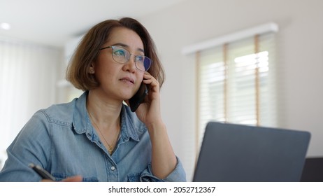 Asia adult people or SME owner woman leader moody sitting tired busy phone call work on laptop computer at desk house office think worry concern give advice on distance job crisis corporate trouble. - Powered by Shutterstock