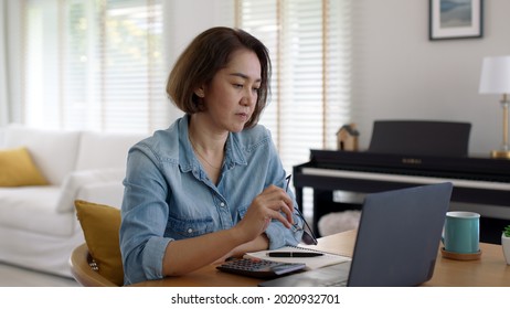 Asia Adult Upset Sad People Or Pensive SME Owner Latin Lady Sit At Home Brownout Work On Desk Laptop Tired Bored Pain In Mental Health Care Issue, Job Loss Life Crisis Or Think Hard Of Debt Loan.